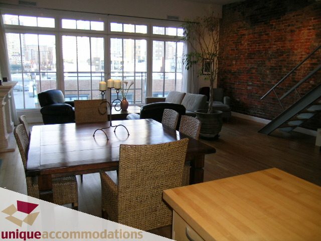 Furnished dining area with large windows, brick wall, and hardwood floors. - PH3  603 - 1155 Mainland, Vancouver Downtown
