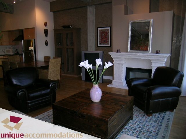 Furnished living room with dark leather furniture, wooden coffee table, and a fireplace. - PH3  603 - 1155 Mainland, Vancouver Downtown