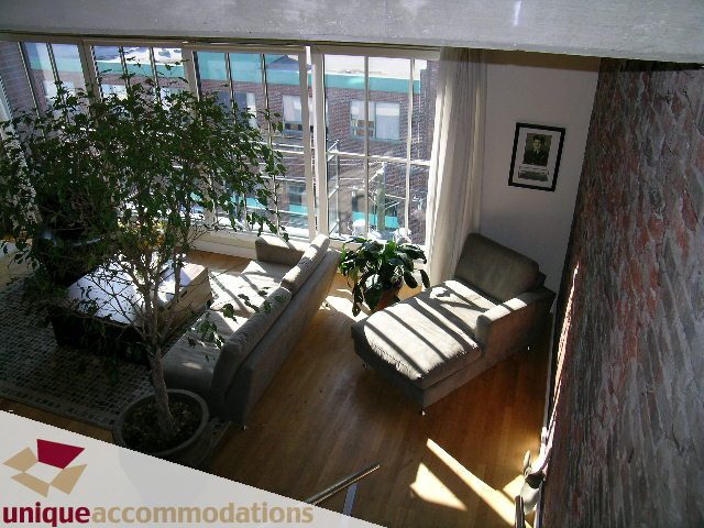 Bright living room with hardwood floors, city view, and exposed brick wall. - PH3  603 - 1155 Mainland, Vancouver Downtown