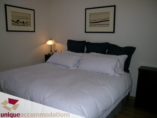 Furnished 2-bedroom condo with two neatly made beds, black pillows, and framed artwork on the wall. - PH3  603 - 1155 Mainland, Vancouver Downtown