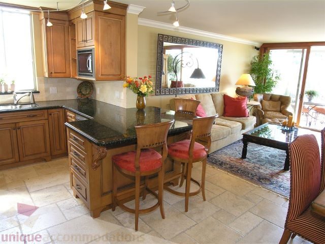 Bright kitchen with granite countertops and a cozy living area featuring a sofa and striped chairs. - 706 - 1600 Howe Street, Vancouver Downtown