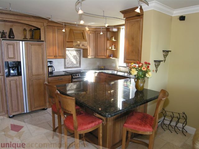 Bright kitchen with granite countertops, wooden cabinets, and a vase of flowers on the island. - 706 - 1600 Howe Street, Vancouver Downtown