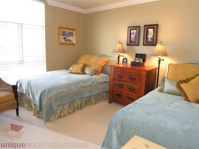 Bright bedroom with twin beds, wooden nightstands, and framed artwork on the wall. - 706 - 1600 Howe Street, Vancouver Downtown