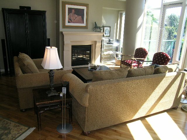 Spacious living room with a cozy fireplace, plush sofas, and large windows offering a serene view. - 1035 Marinaside Crescent, Vancouver Downtown
