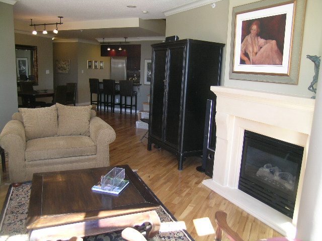 Spacious living room with hardwood floors, cozy armchair, and a fireplace. - 1035 Marinaside Crescent, Vancouver Downtown