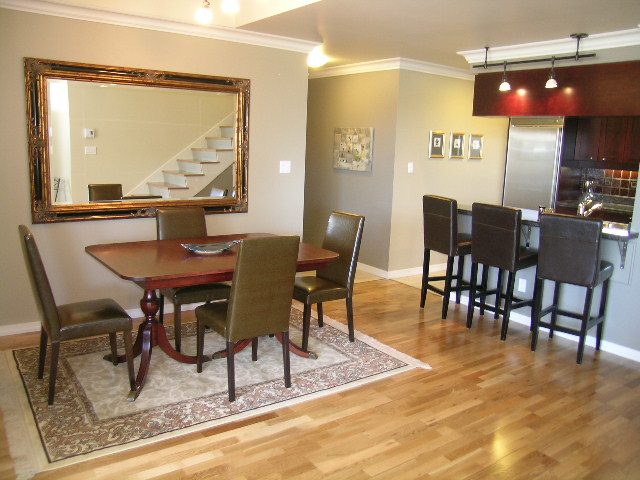 Spacious dining area with hardwood floors, modern chairs, and a large mirror reflecting the staircase. - 1035 Marinaside Crescent, Vancouver Downtown