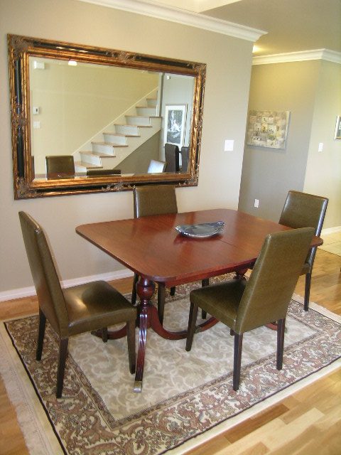 Furnished dining area with wooden table, leather chairs, and a large mirror reflecting the staircase. - 1035 Marinaside Crescent, Vancouver Downtown