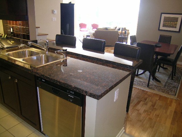 Spacious kitchen with granite countertops and stainless steel appliances, open to a cozy dining area with hardwood floors.