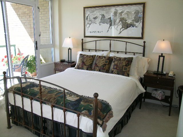Spacious bedroom with a large bed, patterned bedding, and a balcony view. - 1035 Marinaside Crescent, Vancouver Downtown