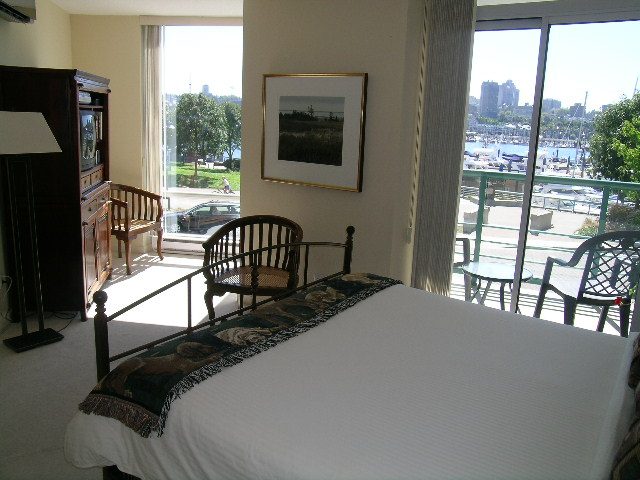 Spacious living room with a city view, furnished with a large bed, dining table, and comfortable seating.