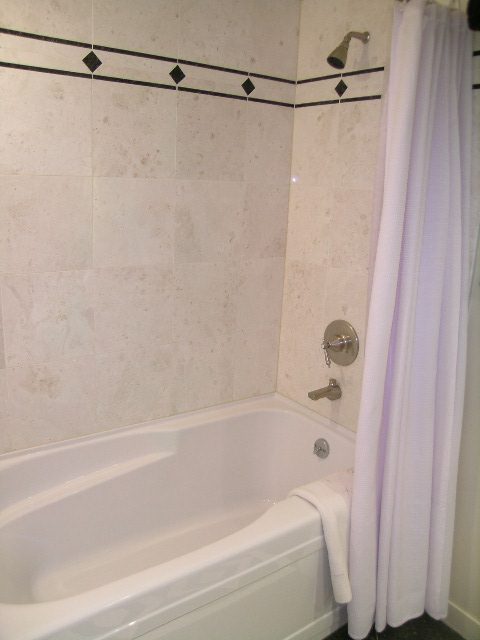 Spacious bathroom with white tile, black accent stripe, and modern fixtures. - 1035 Marinaside Crescent, Vancouver Downtown