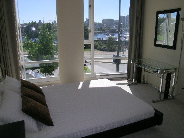 Spacious bedroom with a stunning city view and modern glass furniture. - 1035 Marinaside Crescent, Vancouver Downtown