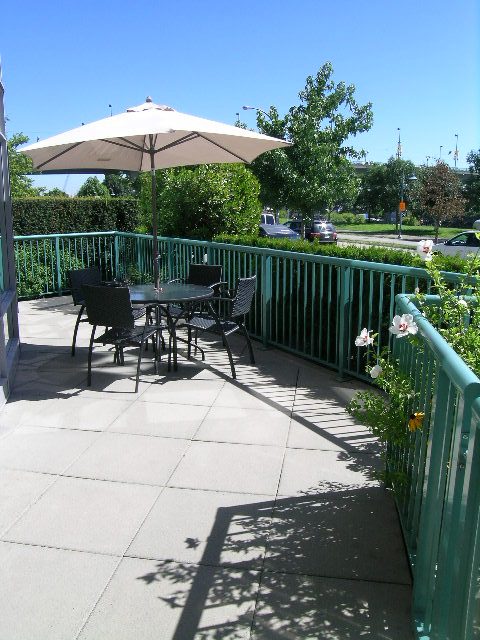 Furnished patio with a large umbrella, green railings, and a view of the street. - 1035 Marinaside Crescent, Vancouver Downtown