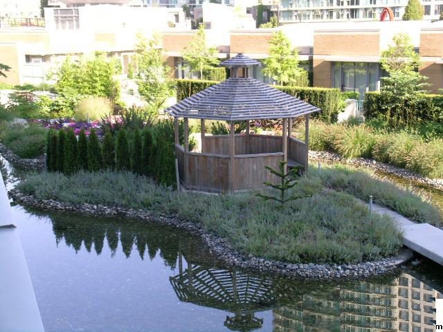 Spacious 2-bedroom + den townhouse with a serene rooftop garden featuring a wooden gazebo and tranquil water feature.