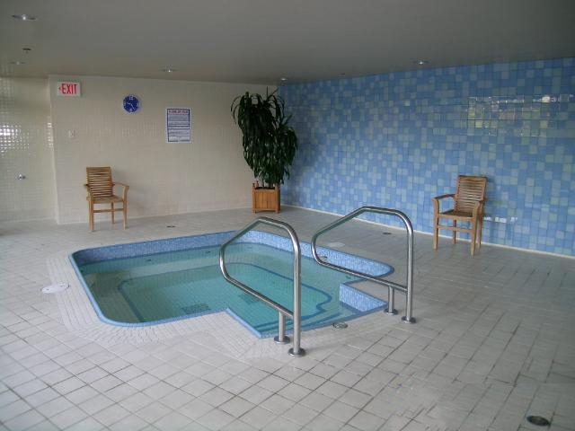 Spacious indoor pool area with tiled walls, wooden chairs, and a serene ambiance. - 1035 Marinaside Crescent, Vancouver Downtown