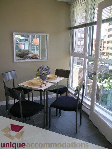 Furnished dining area with city view, modern decor, and large windows. - 707 - 1068 Hornby Street, Vancouver Downtown