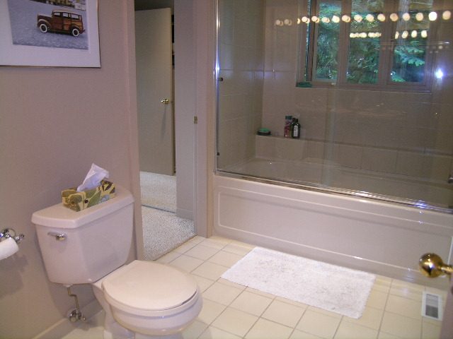 Bathroom with white toilet, glass shower, and tiled floor. - 4527 Stonehaven Avenue, North Vancouver
