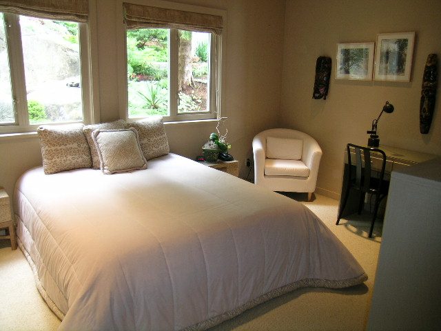 Bright bedroom with white bedding, large windows, and a cozy corner desk setup. - 4527 Stonehaven Avenue, North Vancouver