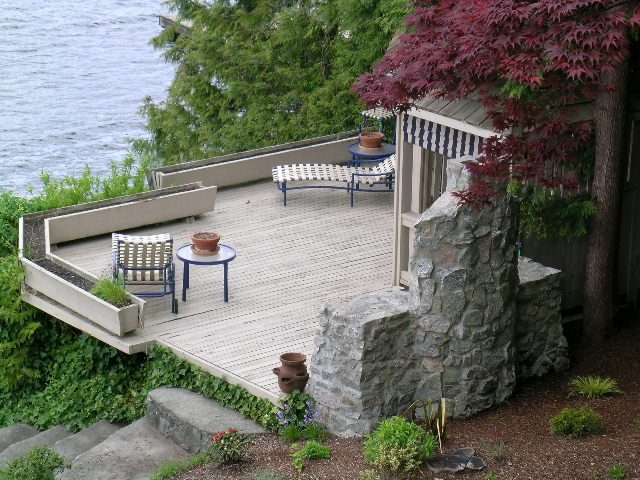Furnished deck overlooking water with stone walls and vibrant foliage. - 4527 Stonehaven Avenue, North Vancouver