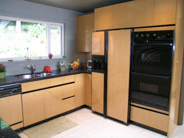 Bright kitchen with light wood cabinets, black appliances, and a window view. - 4527 Stonehaven Avenue, North Vancouver