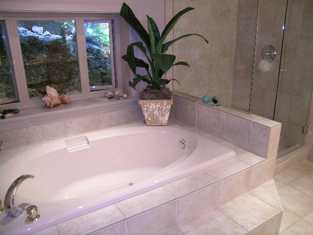 Bathroom with large window, tiled walls, and a built-in bathtub. - 4527 Stonehaven Avenue, North Vancouver