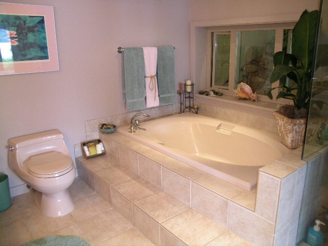 Spacious bathroom with tiled steps and a large bathtub, featuring a coastal decor with seashells. - 4527 Stonehaven Avenue, North Vancouver