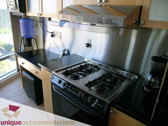 Bright kitchen with stainless steel appliances, black countertops, and a city view. - 1808 - 1003 Burnaby Street, Vancouver Downtown