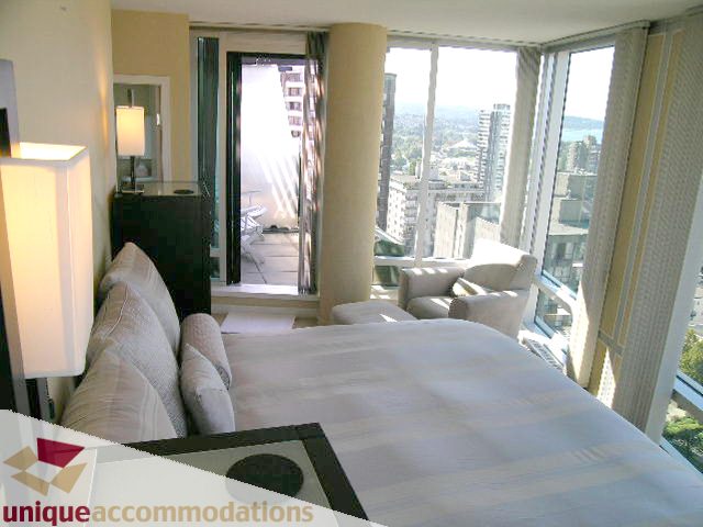 Bright living room with city view and large windows, featuring a cozy sofa and a modern dining table. - 1808 - 1003 Burnaby Street, Vancouver Downtown