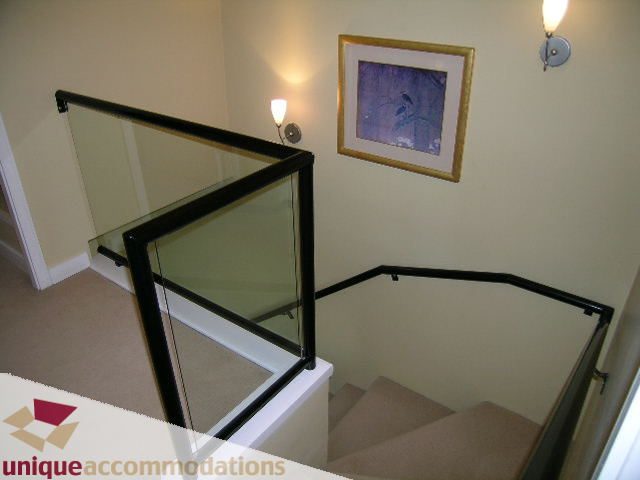 Staircase with glass railings and framed artwork, leading to a cozy den area. - 1808 - 1003 Burnaby Street, Vancouver Downtown