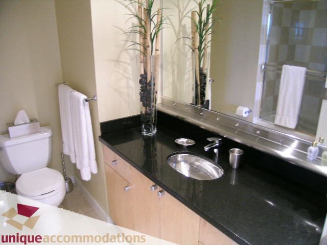 Furnished bathroom with black countertops, wooden cabinets, and a modern sink setup. - 1808 - 1003 Burnaby Street, Vancouver Downtown