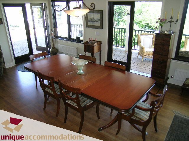 Furnished dining room with wooden table and chairs, hardwood floors, and large windows. - 3664 Creery Ave., West Vancouver