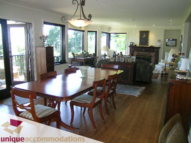 Spacious dining room with large table, hardwood floors, and sliding glass doors leading to a balcony. - 3664 Creery Ave., West Vancouver