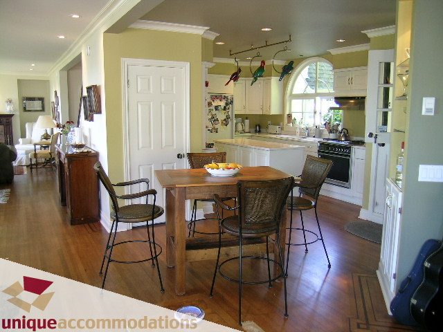 Bright kitchen with hardwood floors, wooden bar stools, and a view of the living area. - 3664 Creery Ave., West Vancouver