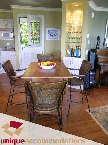 Furnished dining area with wooden table, wicker chairs, and built-in shelves. - 3664 Creery Ave., West Vancouver