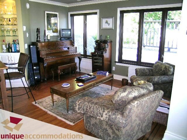 Living room with hardwood floors, patterned couches, and a piano. - 3664 Creery Ave., West Vancouver