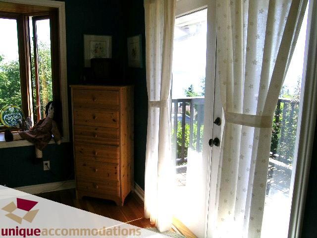 Bright bedroom with wooden dresser and hardwood floors, natural light from large windows. - 3664 Creery Ave., West Vancouver