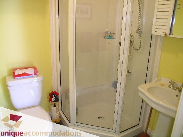 Bright bathroom with glass shower, white sink, and yellow walls. - 3664 Creery Ave., West Vancouver