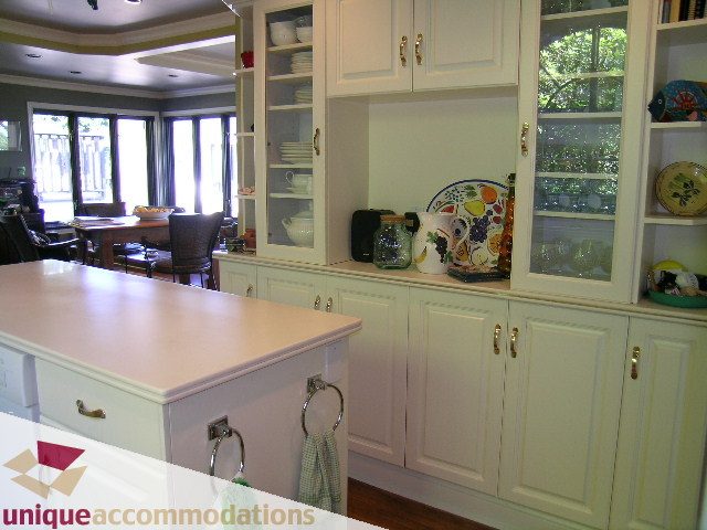Bright kitchen with white cabinets, granite countertops, and a view of the garden. - 3664 Creery Ave., West Vancouver