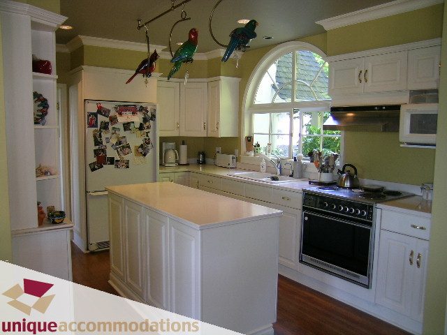 Bright kitchen with white cabinetry, hardwood floors, and a view of the backyard. - 3664 Creery Ave., West Vancouver