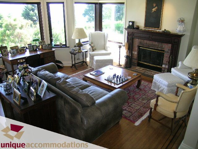 Spacious living room with large windows, hardwood floors, and a cozy fireplace. - 3664 Creery Ave., West Vancouver