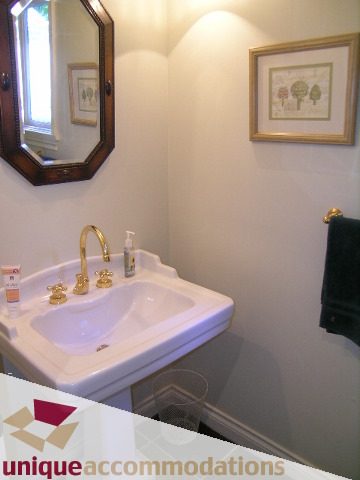 Bright bathroom with white sink, gold faucet, and framed artwork. - 3664 Creery Ave., West Vancouver