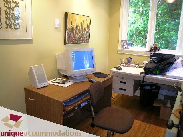 Bright home office with wooden desk, computer, and large window with city view. - 3664 Creery Ave., West Vancouver