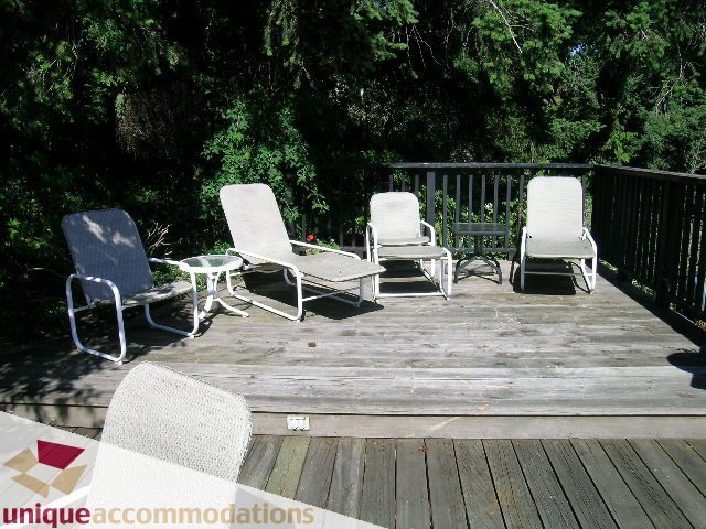 Furnished deck with outdoor chairs and table, surrounded by greenery. - 3664 Creery Ave., West Vancouver