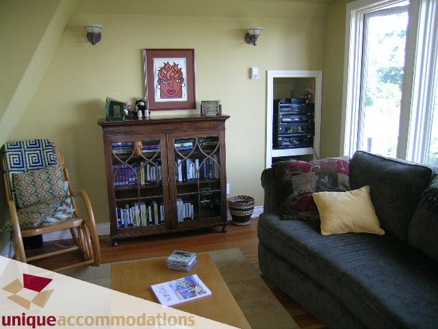 Living room with hardwood floors, bookshelves, and a large window. - 3664 Creery Ave., West Vancouver
