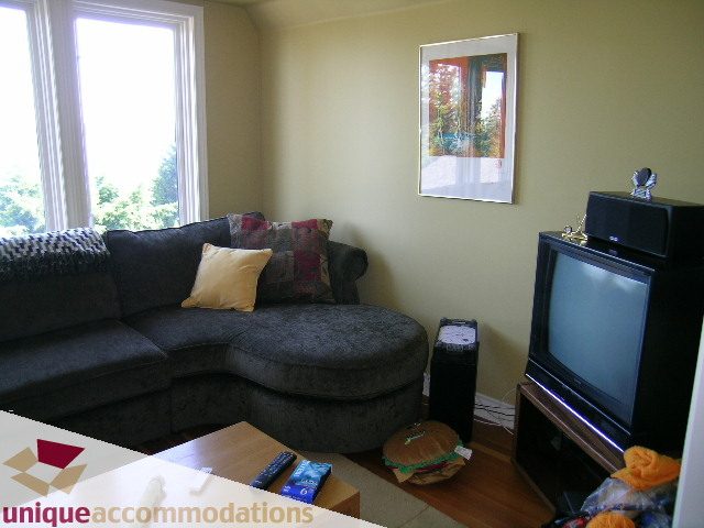 Living room with a sectional sofa, hardwood floors, and a window view. - 3664 Creery Ave., West Vancouver