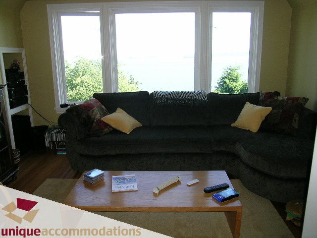 Living room with large windows, hardwood floors, and a comfortable sofa set. - 3664 Creery Ave., West Vancouver