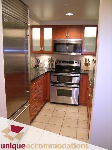 Bright kitchen with stainless steel appliances, wooden cabinets, and tiled flooring. - 322 - 1228 Marinaside Crescent, Vancouver Downtown