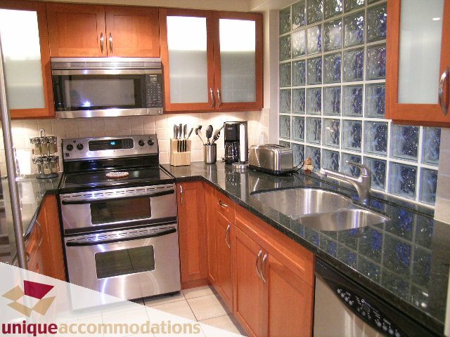 Bright kitchen with stainless steel appliances, glass block backsplash, and wooden cabinets. - 322 - 1228 Marinaside Crescent, Vancouver Downtown