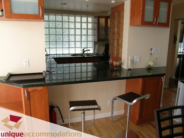 Furnished kitchen with dark countertops, hardwood floors, and a glass block wall. - 322 - 1228 Marinaside Crescent, Vancouver Downtown