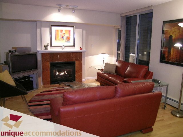 Furnished living room with red leather couches, fireplace, and hardwood floors. - 322 - 1228 Marinaside Crescent, Vancouver Downtown